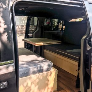 Canapé, lit et table à l'intérieur d'un van avec location de kit de conversion