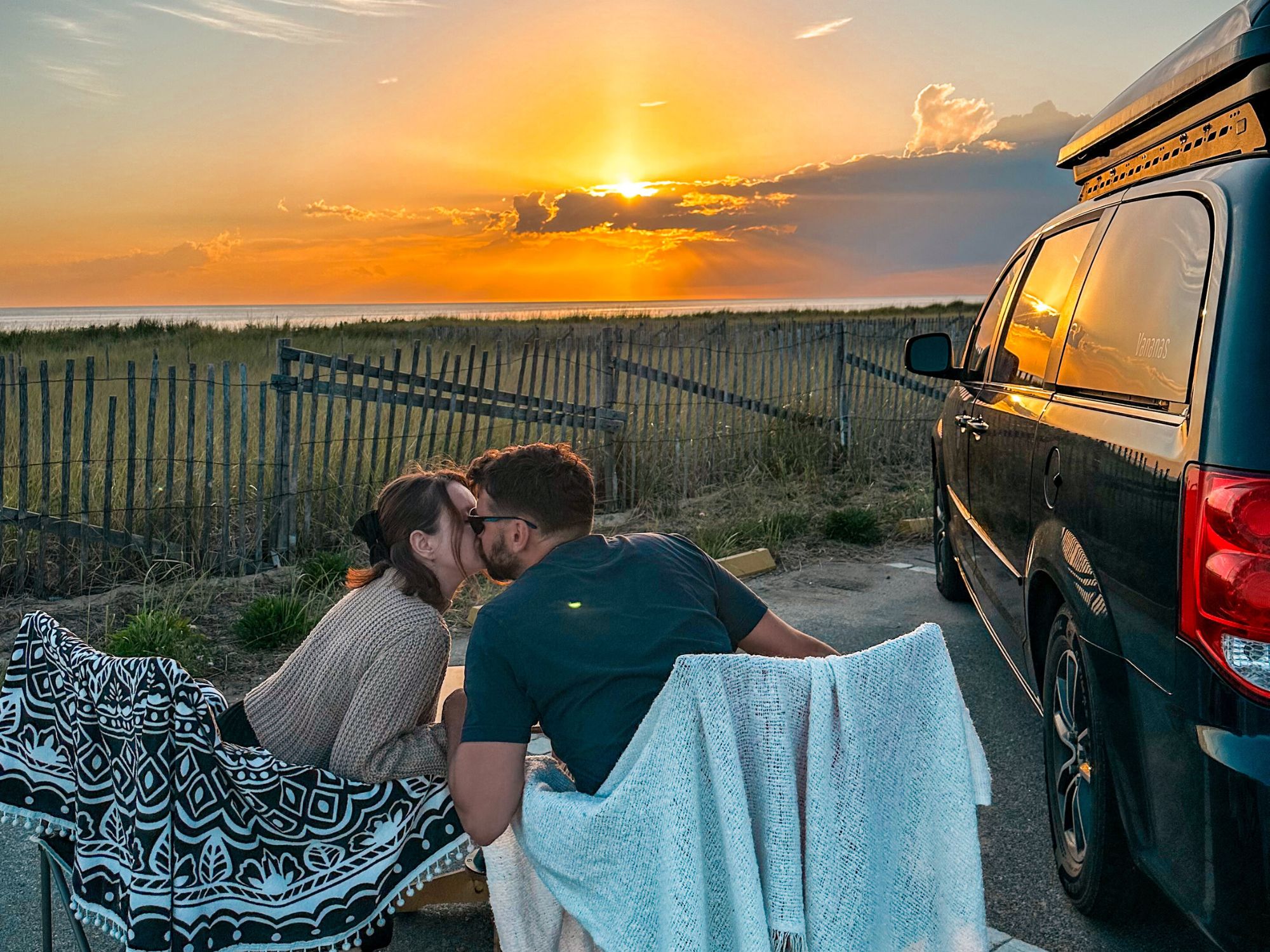 couple in front of their converted minivan at sunset