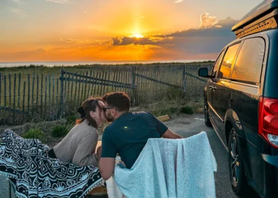 couple au coucher du soleil à côté de la minivan aménagée